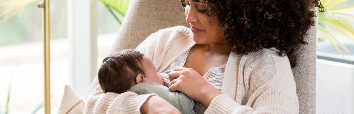 Young mom nurses her newborn baby while in the child's nursery.