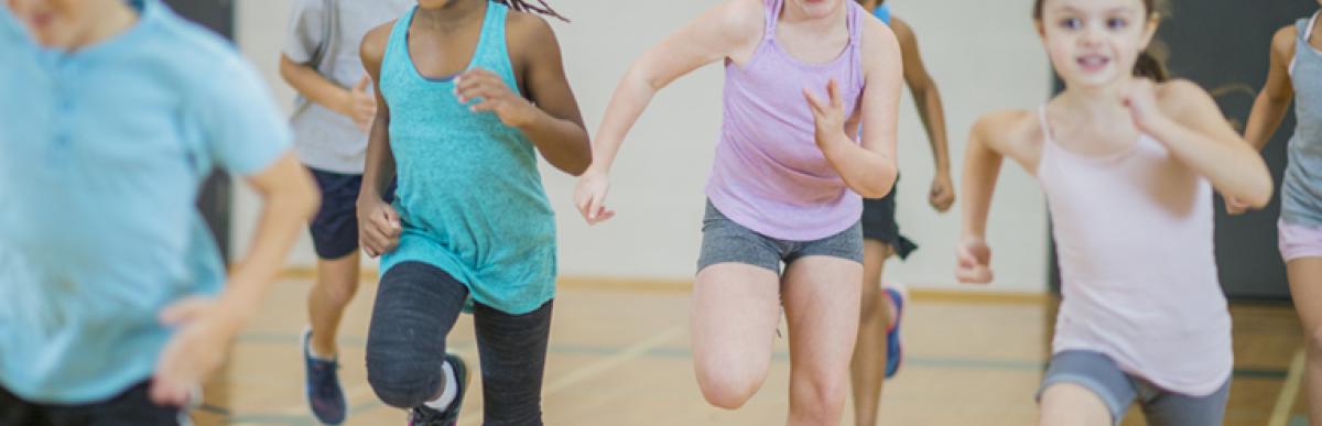 A group of children run across a gym floor