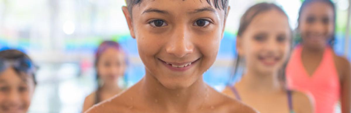 Smiling children with goggles on their heads at an indoor pool