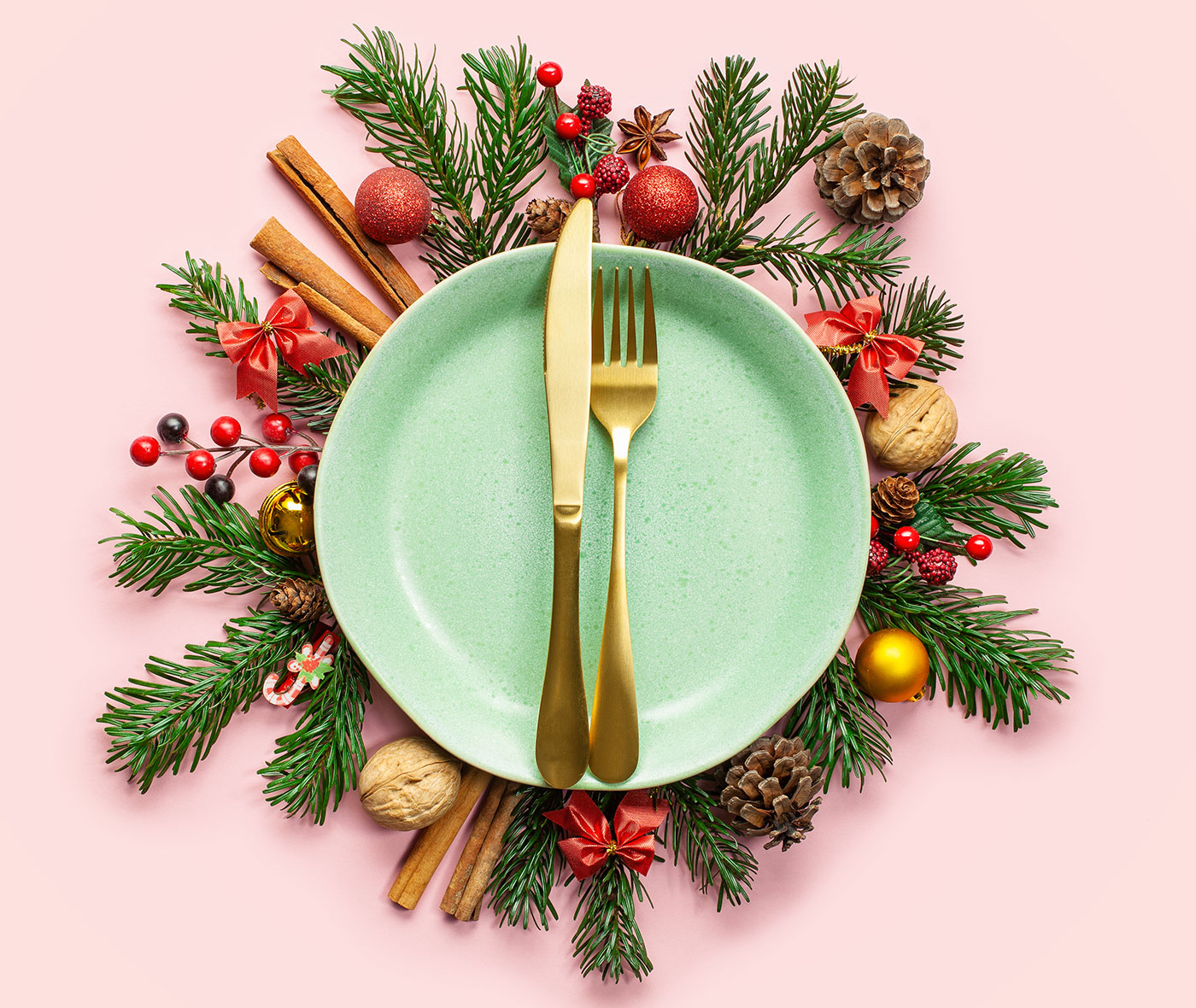 Plate, winter fir branches, cones and Christmas decoration on pink background.