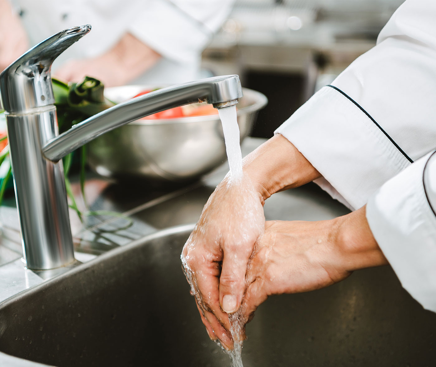 Chef washing hands in commercial kitchen while preparing food