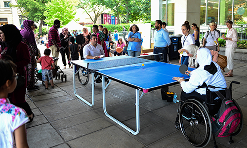 People playing table tennis in wheelchairs while spectators watch