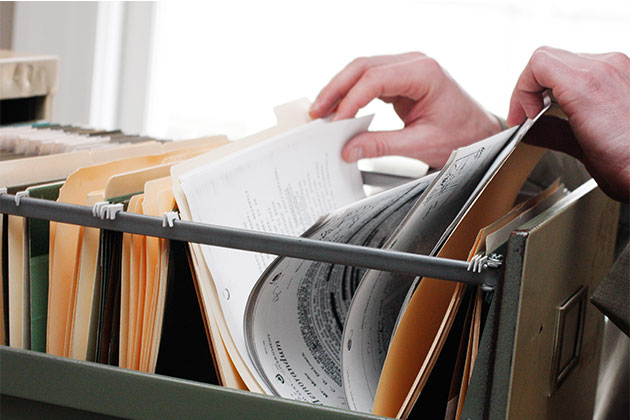 Person searching through file cabinet for records