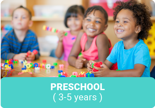 Smiling preschool children at a table with blocks