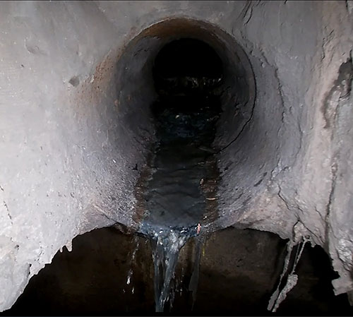 Picture of combined sewer with noticeable flow dropping out and into the storm sewer. 