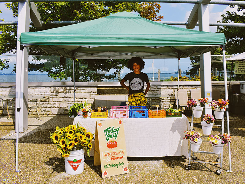 Woman standing behind the table at a flower stand.