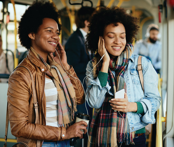 2 women on a bus sharing headphones