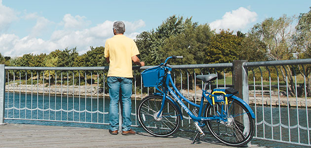 Man standing beside bike share bike overlooking water