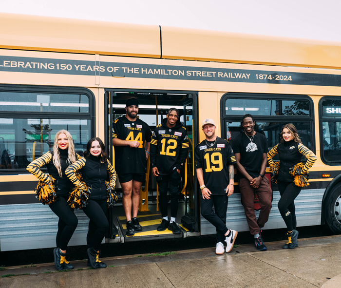 Ticats and cheerleaders in front of bus