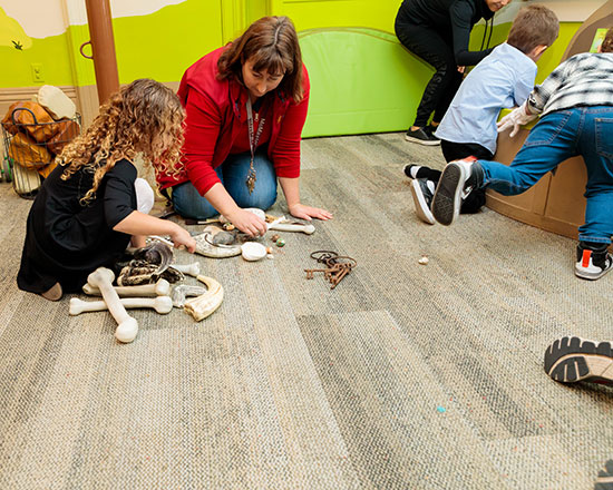 Children's museum archeology event. Children examine bones and fossils.