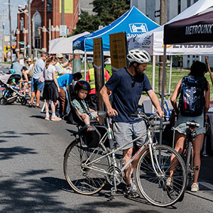 Man with bike and other people visiting Booths on the closed street for Open Streets event in June 2024