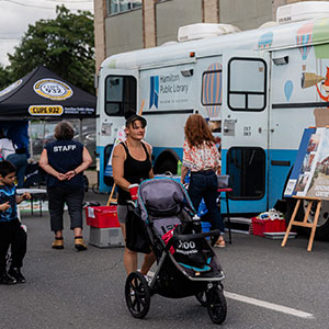 Women pushing stroller outside of Library's Bookmobile on the closed street for Open Streets event in June 2024