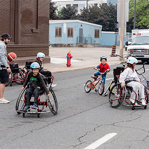 Children playing wheelchair basketball and biking in closed street during Open Streets event in May 2024