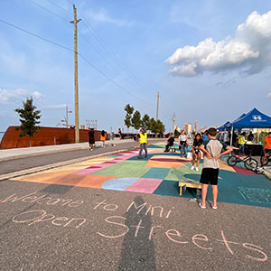 Mini Open Streets event with sidewalk chalk, event tents and people in the closed street