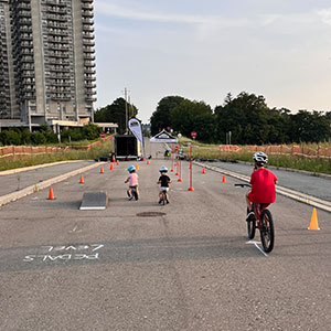 Children wearing helmets riding bikes in course on closed street at Mini Open Streets at Pier 8