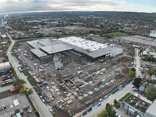 Elevator shafts are being constructed in the foreground. The MSF structure for the bus storage building and roofing (white rooftop) are complete. 