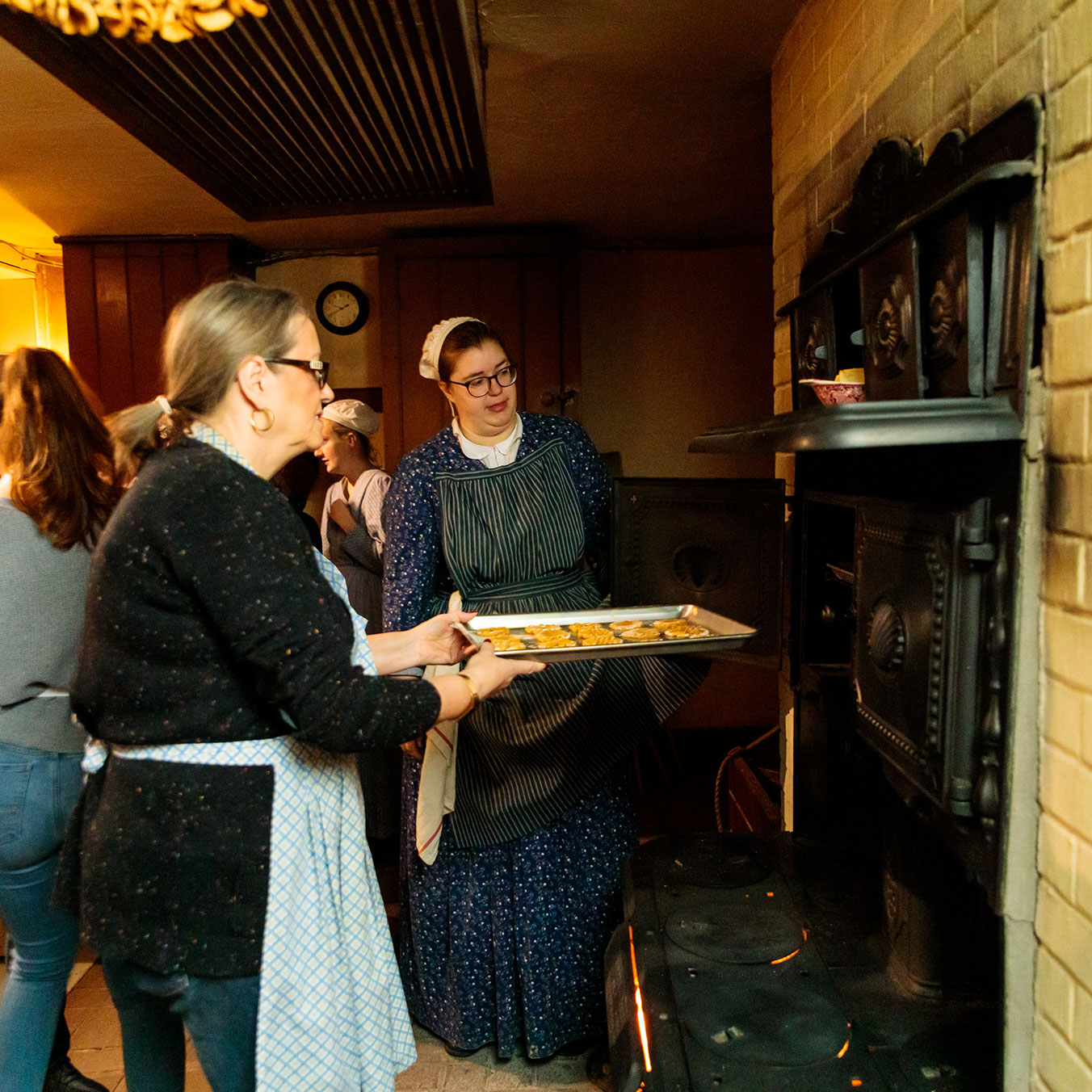 Cook demonstrator putting a tray of cookies in the oven during cooking workshop