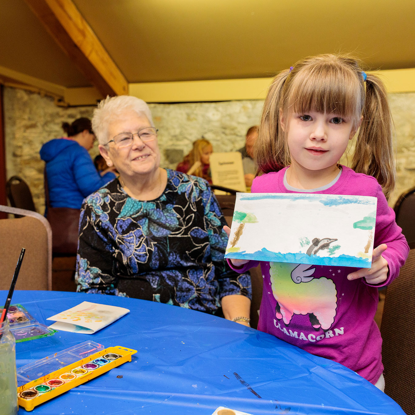 Young girl showing painting as proud grandmother smiles