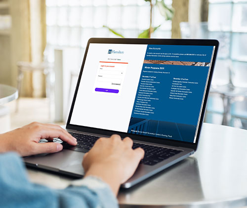 persons hands on a laptop logging into the new City of Hamilton recreation registration website