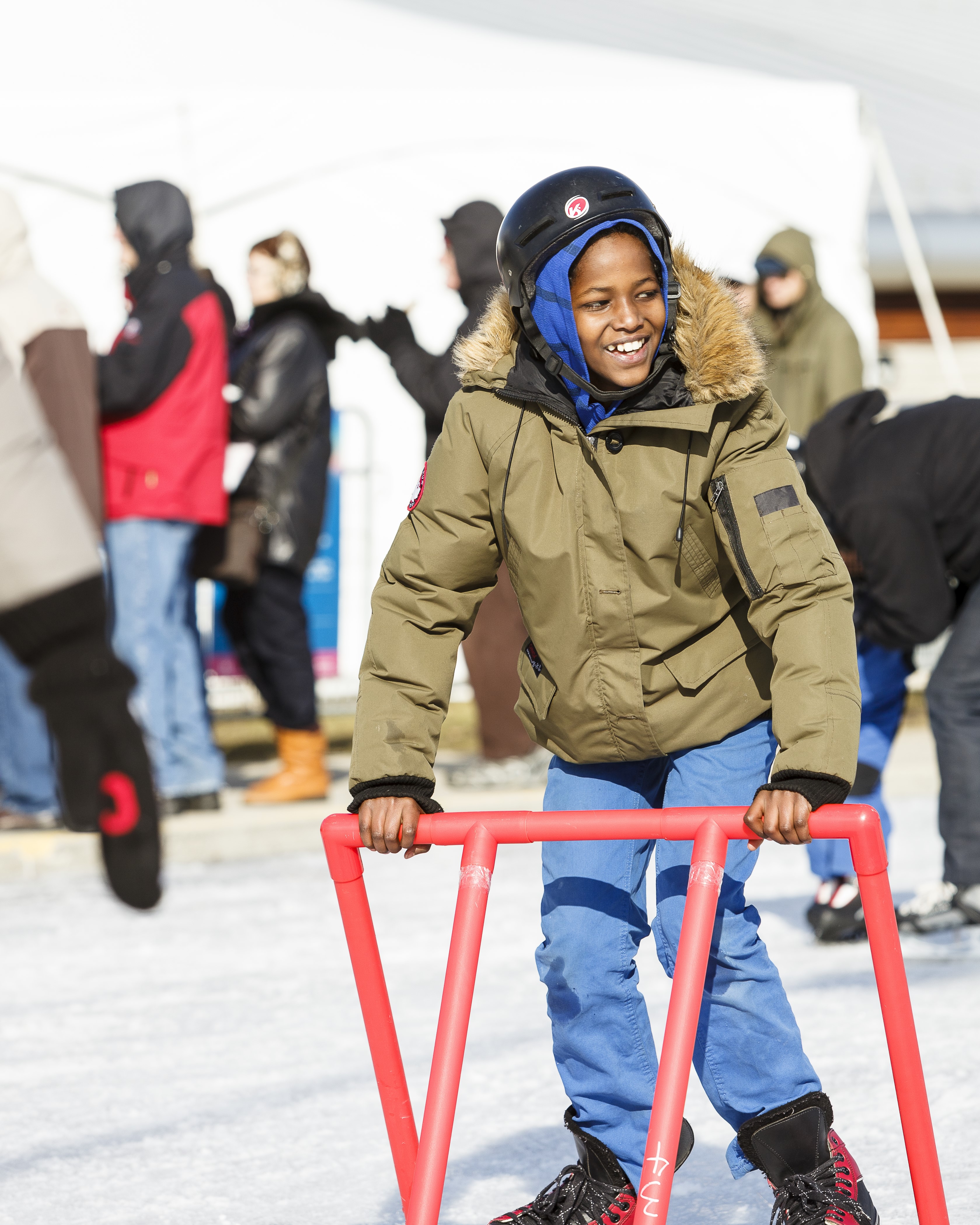 Smiling child using a skate support to ice skate during Hamilton Winter fest