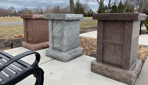 Three stone monuments in a cemetery standing side by side