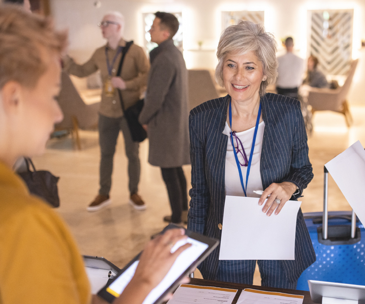 Business woman with grey hair smiling at person holding a tablet.