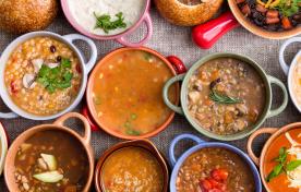 top view of various bowls of soups and stews in ceramic and bread bowls