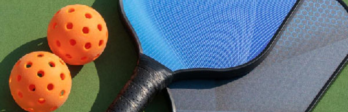 image of 2 pickleball paddles and balls on a court