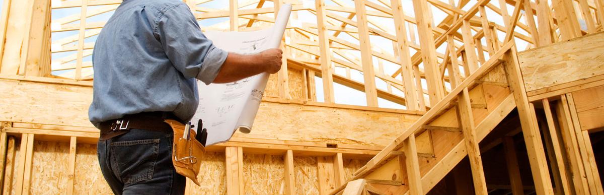 Contractor reviewing construction plans in wood framed house