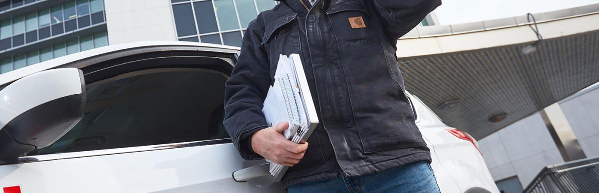 Building Inspector talking on phone standing outside City Hall with Building Division vehicle