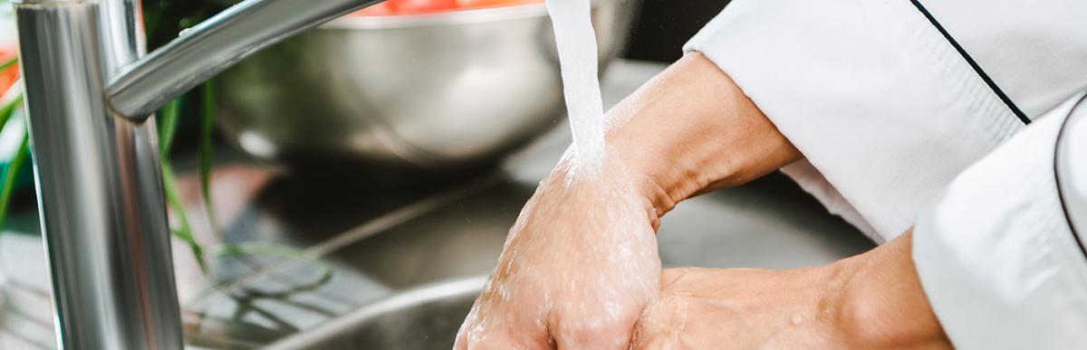 Chef washing hands in commercial kitchen while preparing food