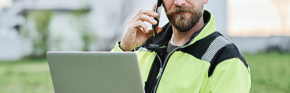 Construction worker on phone holding laptop