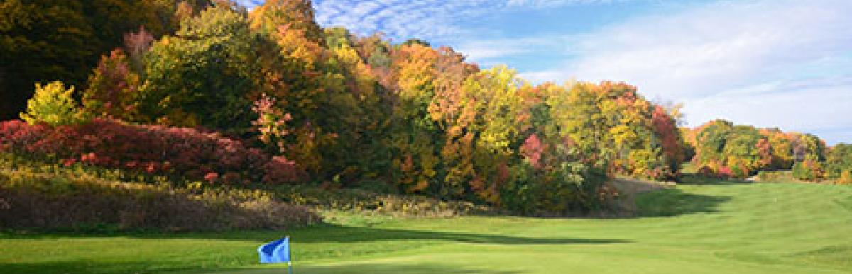 18th hole at Beddoe golf course, fairway and flag with fall leaves on trees.