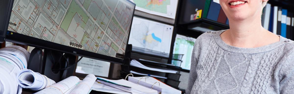 Woman sitting at desk with computer and building drawings