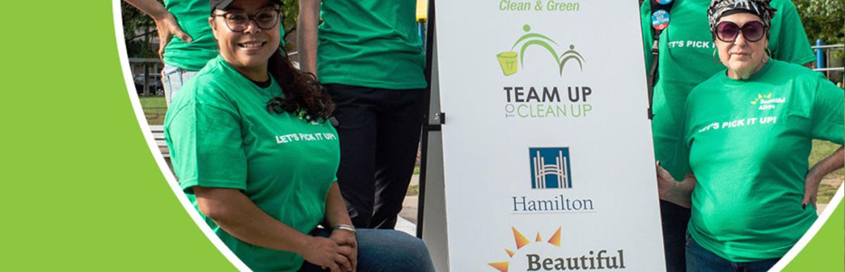 Volunteer cleanup team posing around a partners logo board, Keep Hamilton Clean & Green, Team Up to Clean Up, City of Hamilton, Beautiful Alleys logos