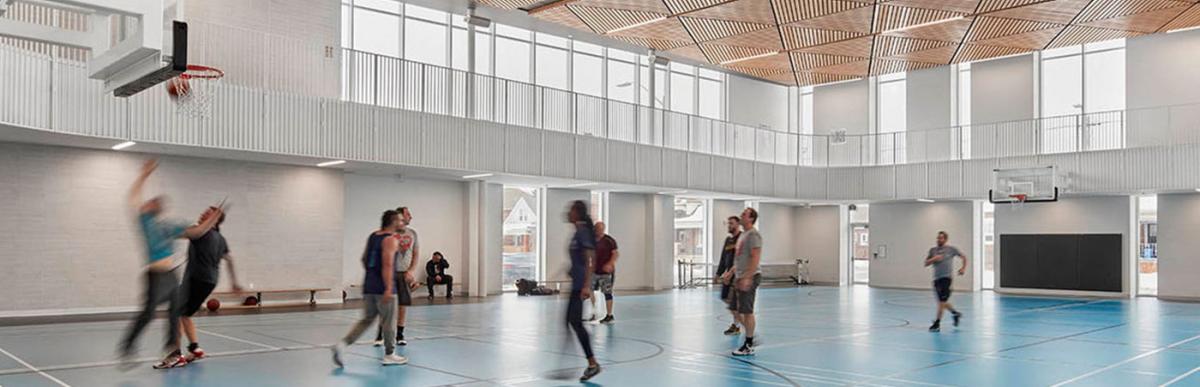 A multi-ethnic group of adults playing basketball in the gym.