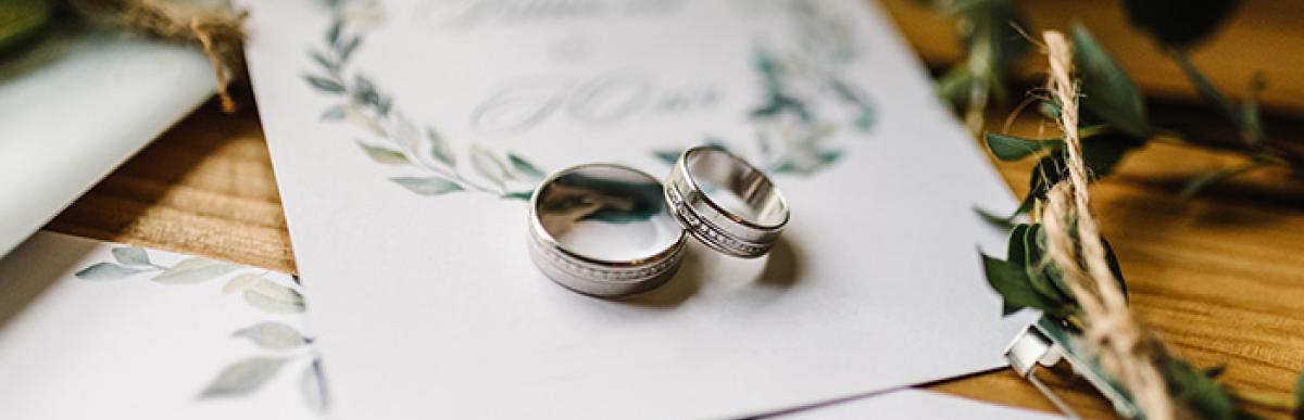 Wedding rings on an invitation surrounded by flowers