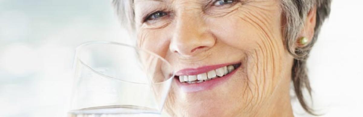 Older woman smiling drinking a glass of water