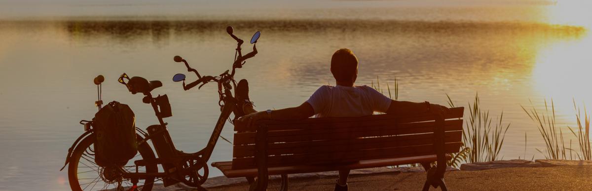 Silhouette of person on a bench overlooking water