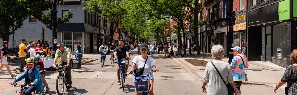 Groups of people walking and biking along closed street during Open Streets event in May 2024