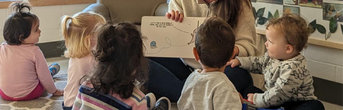 children sitting around a childcare worker