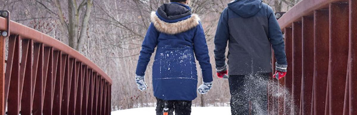 two people in snowshoes walking over a snowy bridge