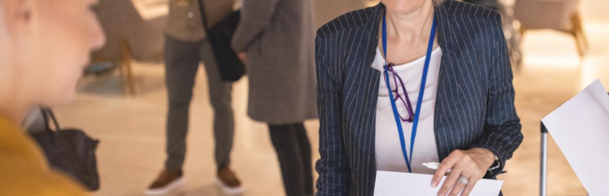 Business woman with grey hair smiling at person holding a tablet.