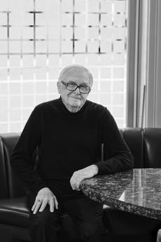 black and white photo of man with glasses sitting at a table